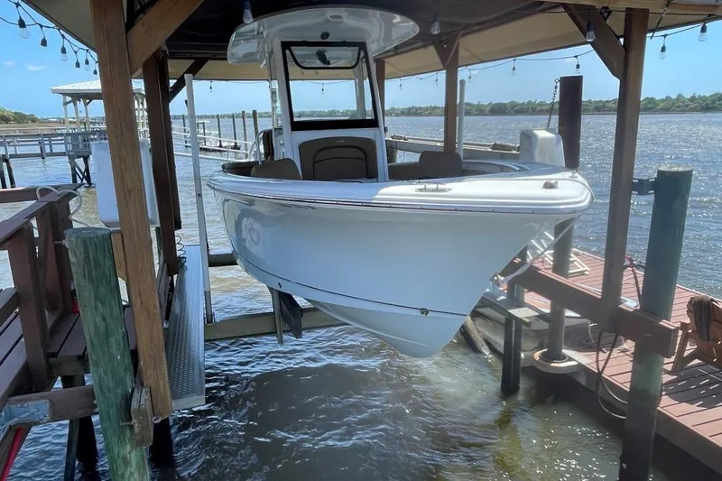 Slide: The Image of 2021 Sea Hunt 239 Ultra SE boat docked on a lift by the water. - 9