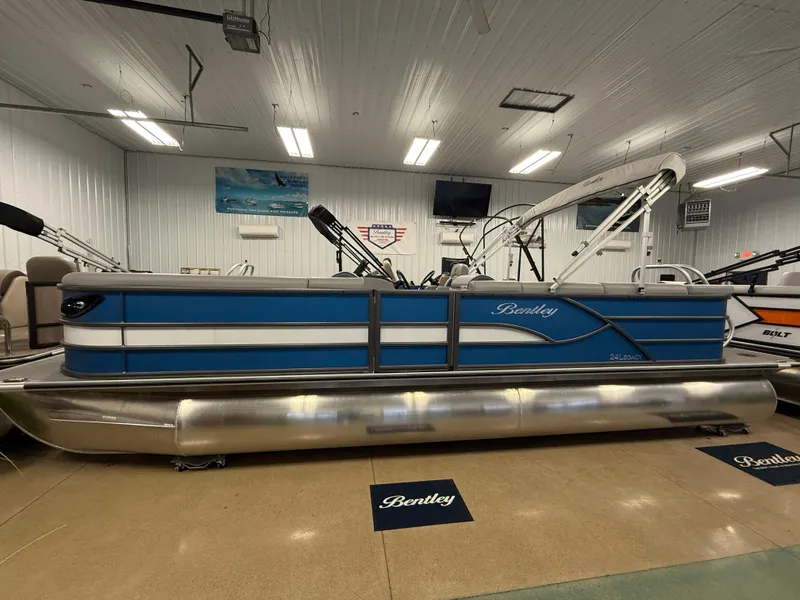 Slide: The Image of 2025 Bentley Pontoons Legacy 240 Cruise in showroom, blue and white design, side view. - 0