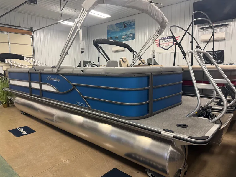 Slide: The Image of 2025 Bentley Pontoons Legacy 240 Cruise in showroom, blue exterior, sleek design. - 1