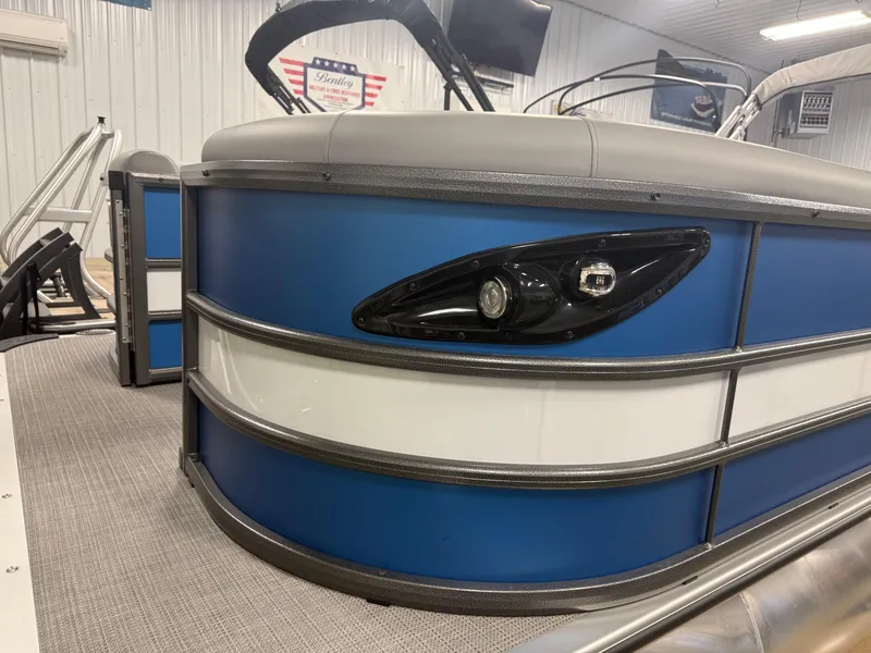 Slide: The Image of 2025 Bentley Pontoons Legacy 240 Cruise, blue and white exterior, in showroom setting. - 4