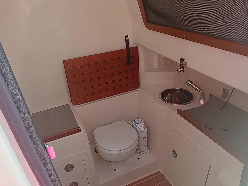 Slide: The Image of 2025 Grady-White Canyon 306 boat bathroom with toilet, sink, and wooden accents. - 19