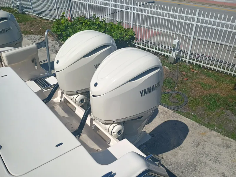 Slide: The Image of 2025 Grady-White Canyon 306 with dual Yamaha outboard engines, parked near a white fence. - 34