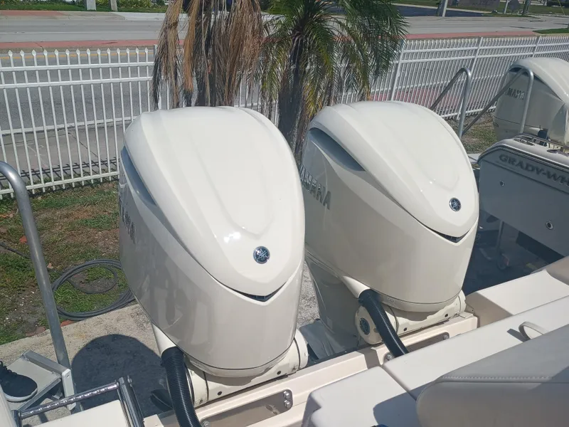 Slide: The Image of 2025 Grady-White Canyon 306 with dual Yamaha outboard engines, parked near a white fence. - 36