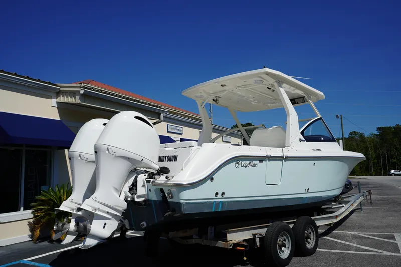 Slide: The Image of 2018 Edgewater 262 CX boat on trailer with dual outboard engines, parked outdoors. - 1