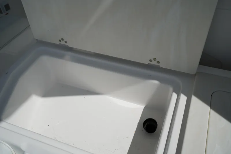 Slide: The Image of 2018 Edgewater 262 CX boat compartment with drain plug, white interior. - 18