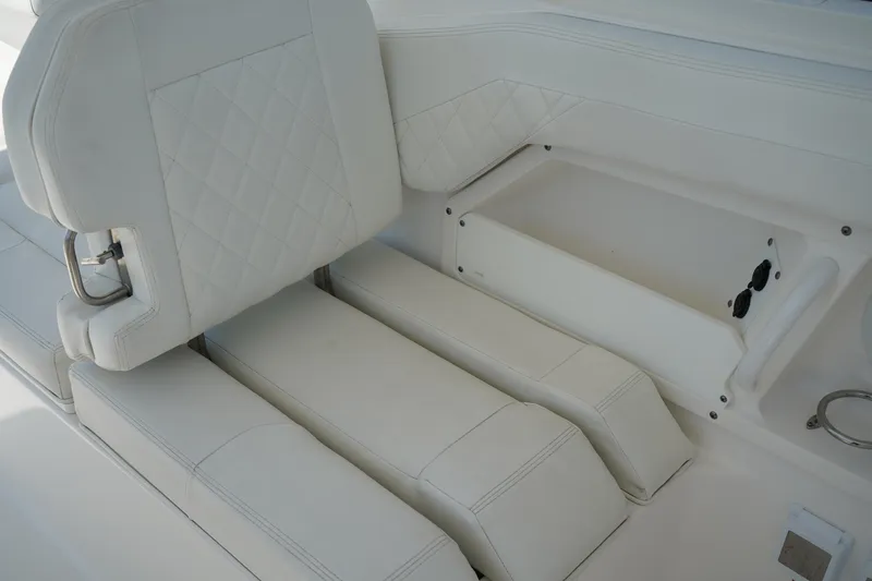 Slide: The Image of 2018 Edgewater 262 CX boat interior with white cushioned seating and storage compartment. - 27