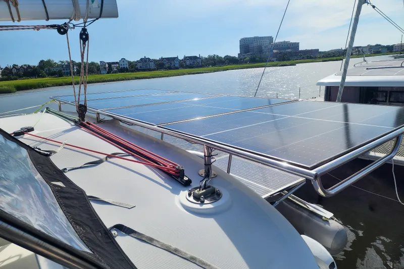 Slide: The Image of 2012 Lagoon 400 catamaran with solar panels on deck, docked by a scenic waterfront. - 16