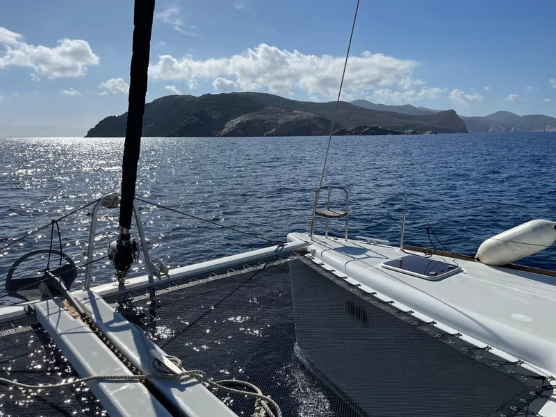 Slide: The Image of Catamaran Lagoon 400 sailing near rocky coastline under clear blue sky. - 5