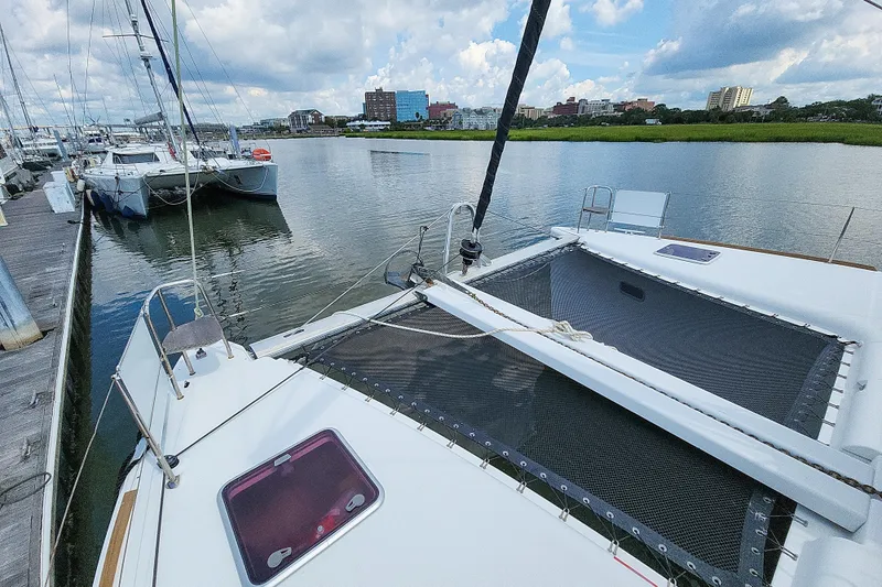 Slide: The Image of 2012 Lagoon 400 catamaran docked in a marina with cityscape background. - 6