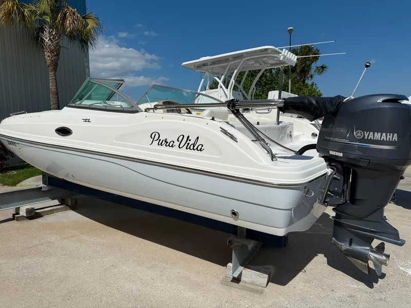 Slide: The Image of 2012 Hurricane SunDeck 217 OB boat with Yamaha engine, named "Pura Vida," on display outdoors. - 1