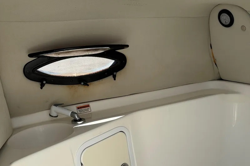 Slide: The Image of Interior view of a 2012 Hurricane SunDeck 217 OB boat, featuring a small window and faucet. - 17