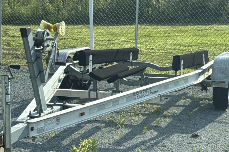 Slide: The Image of Boat trailer for 2012 Hurricane SunDeck 217 OB, parked on gravel near a fence. - 18
