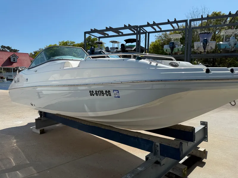 Slide: The Image of 2012 Hurricane SunDeck 217 OB boat on trailer, white exterior, parked outdoors. - 3