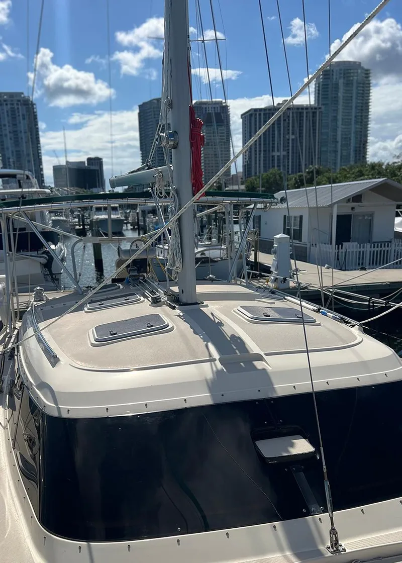 Slide: The Image of 1998 Island Packet Cat 35 sailboat docked in a marina with city skyline. - 7