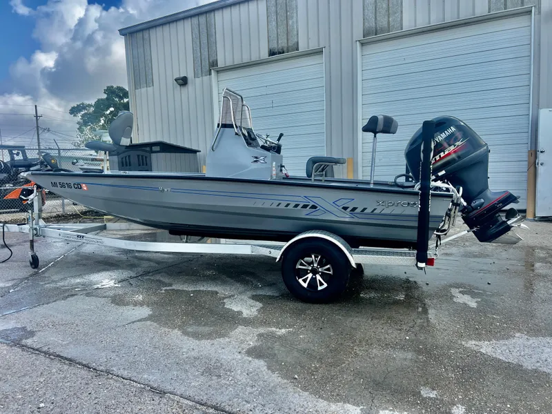 Slide: The Image of 2023 Xpress H190B boat on trailer, parked outside industrial building. - 1