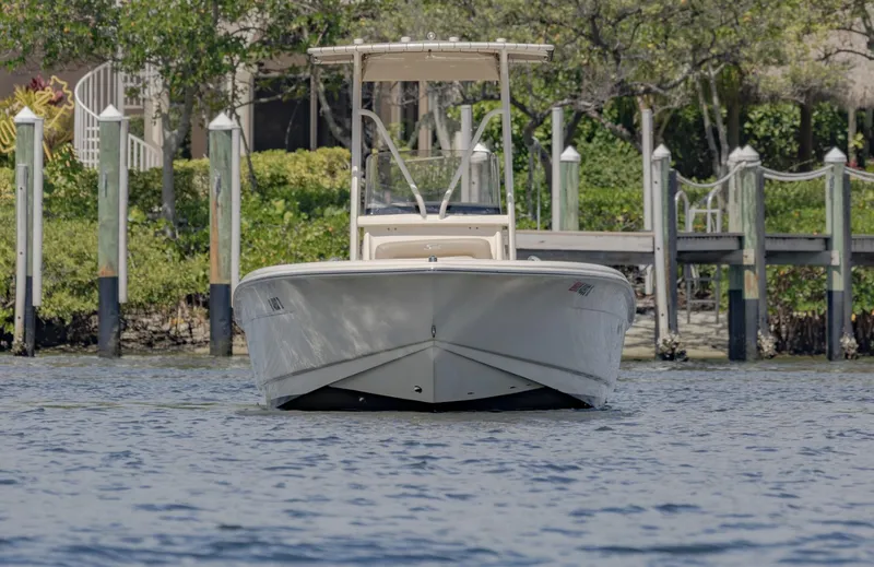 Slide: The Image of 2023 Scout 195 Sportfish boat on water near dock and greenery. - 2