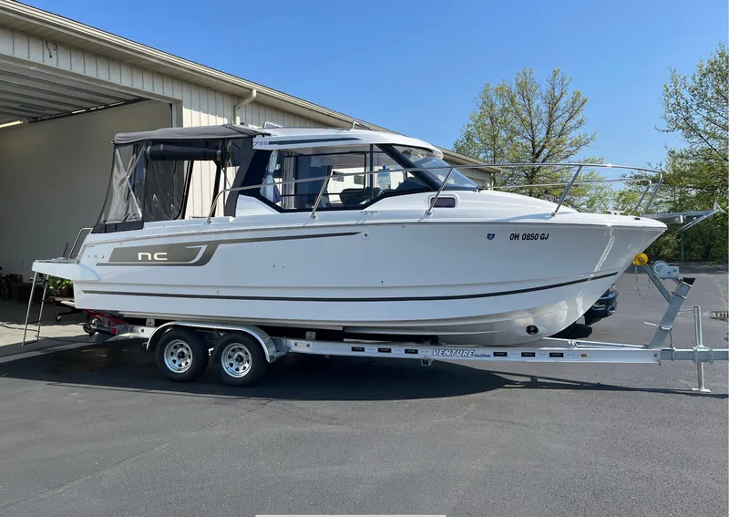 Slide: The Image of 2022 Jeanneau NC 795 boat on trailer, parked outdoors near a building. - 0
