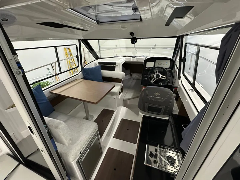 Slide: The Image of Interior of 2022 Jeanneau NC 795 boat, featuring seating, table, and helm station. - 11