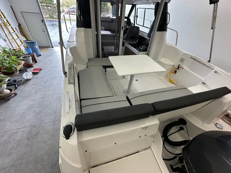 Slide: The Image of 2022 Jeanneau NC 795 boat interior with seating and table in a garage setting. - 21
