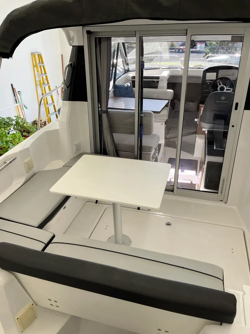 Slide: The Image of 2022 Jeanneau NC 795 boat interior with seating and table, featuring sliding glass doors. - 23