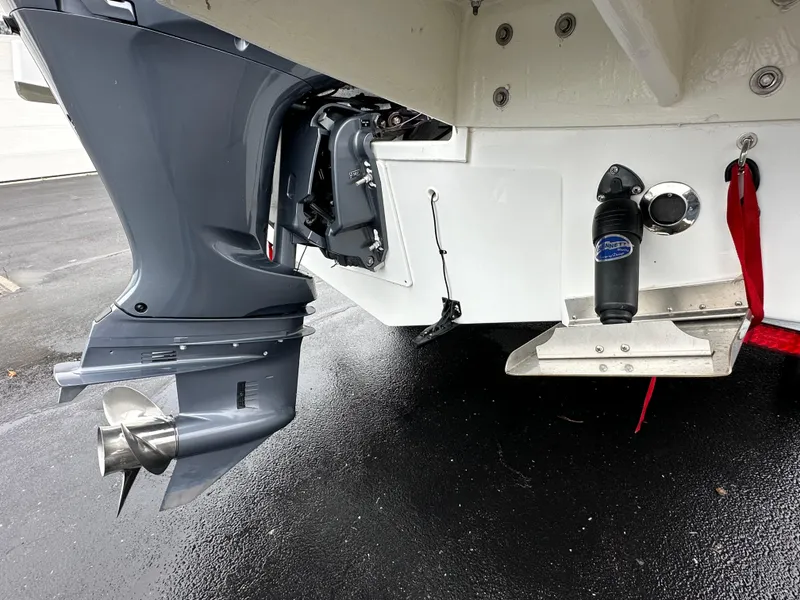 Slide: The Image of 2022 Jeanneau NC 795 boat stern with outboard motor and propeller on wet pavement. - 27