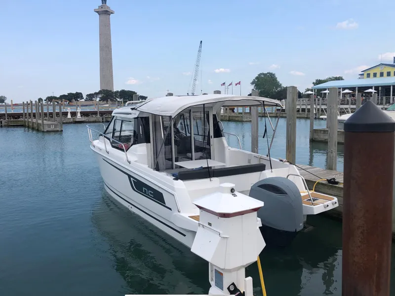 Slide: The Image of 2022 Jeanneau NC 795 boat docked in a marina with a tall monument in the background. - 4