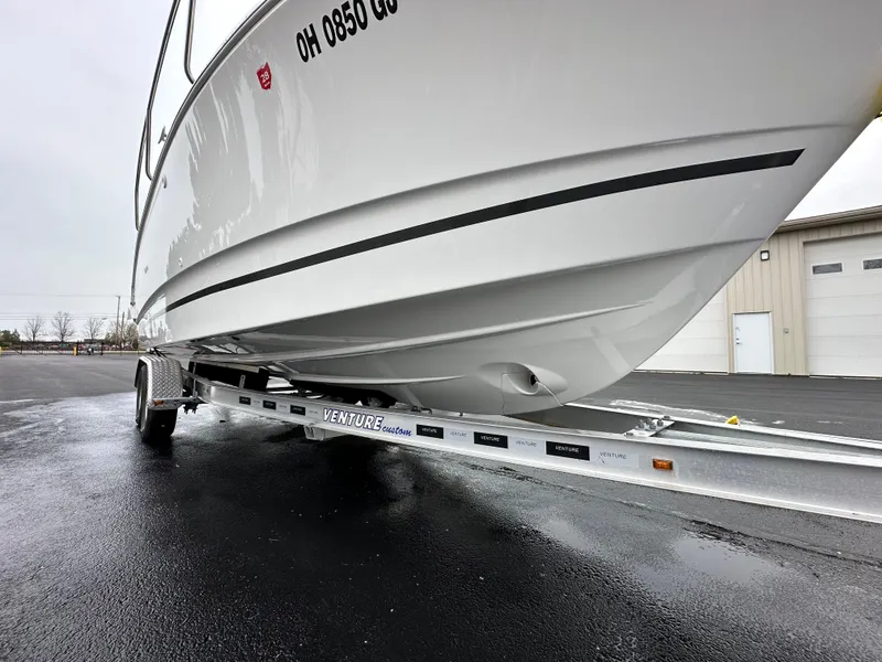 Slide: The Image of 2022 Jeanneau NC 795 boat on trailer, parked on wet pavement near a building. - 7