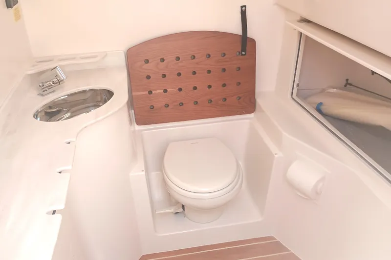 Slide: The Image of 2025 Grady-White Canyon 326 boat bathroom with toilet, sink, and storage. - 13