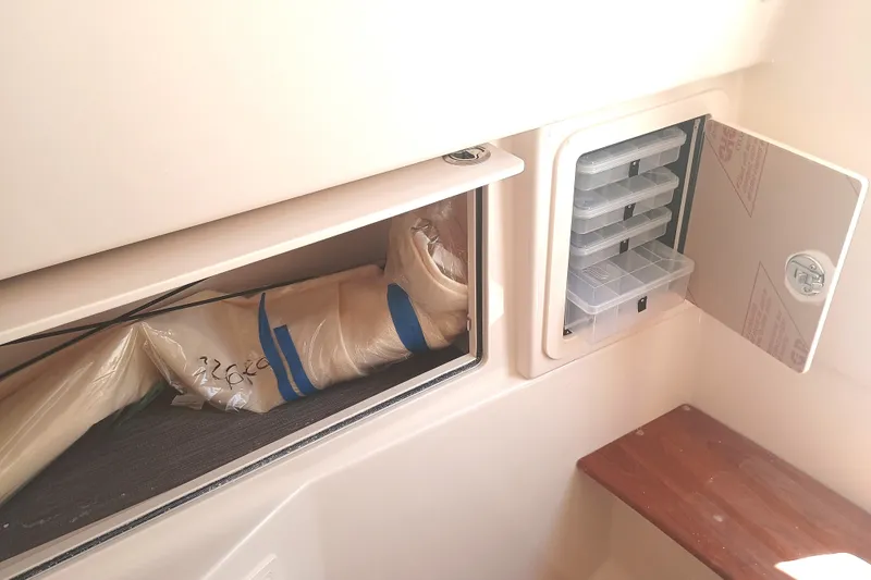 Slide: The Image of Storage compartments in a 2025 Grady-White Canyon 326 boat, featuring organized tackle boxes. - 16