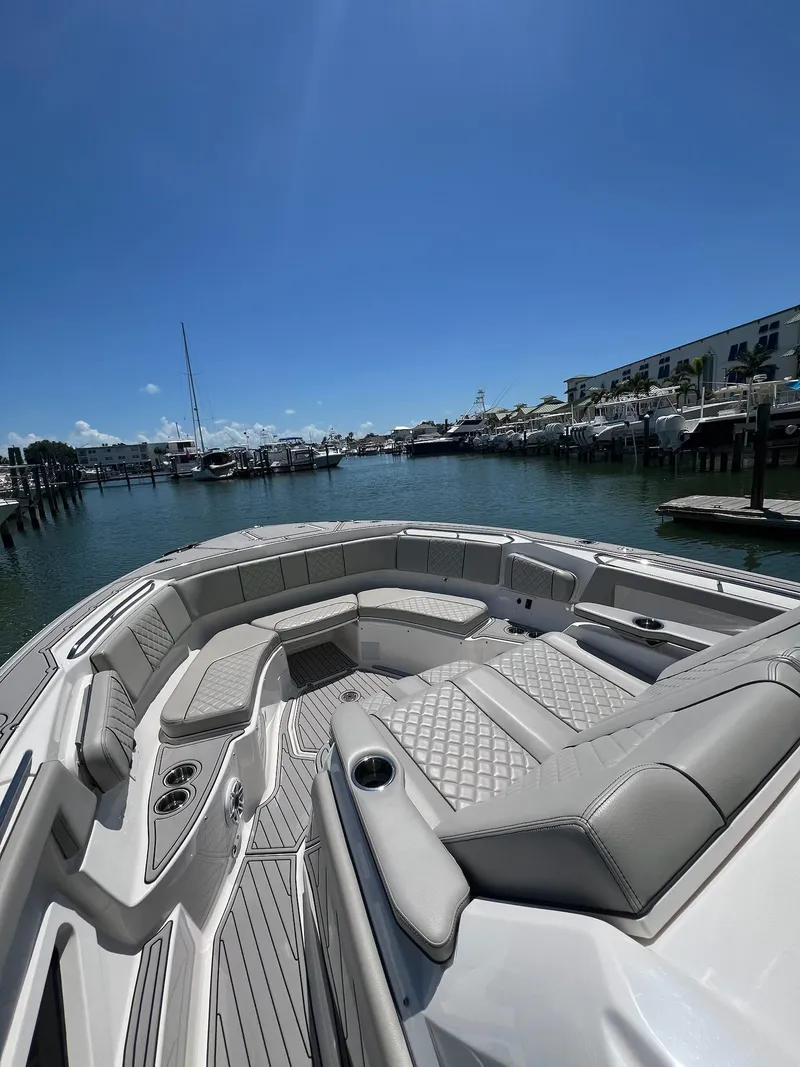 Slide: The Image of 2023 Pursuit S 378 Sport boat with luxurious seating, docked in a sunny marina. - 16