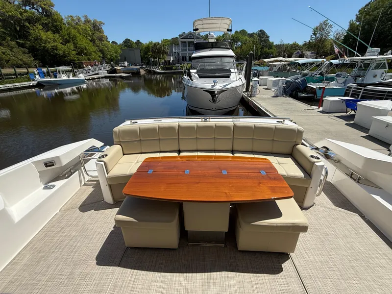 Slide: The Image of 2016 Tiara Yachts 50 Coupe with elegant outdoor seating and table, docked at a marina. - 10