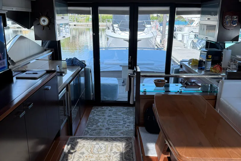 Slide: The Image of Interior of 2016 Tiara Yachts 50 Coupe, featuring modern kitchen and dining area with marina view. - 17