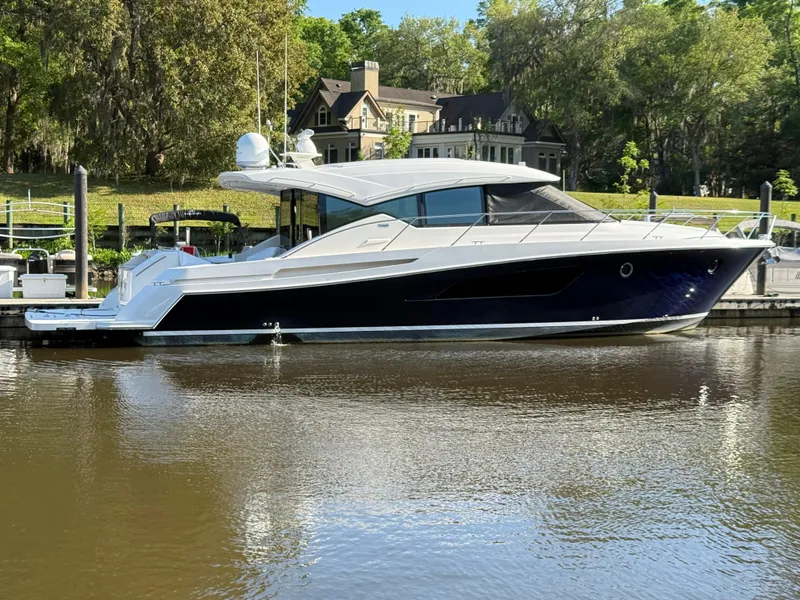 Slide: The Image of 2016 Tiara Yachts 50 Coupe docked by a scenic waterfront home. - 2
