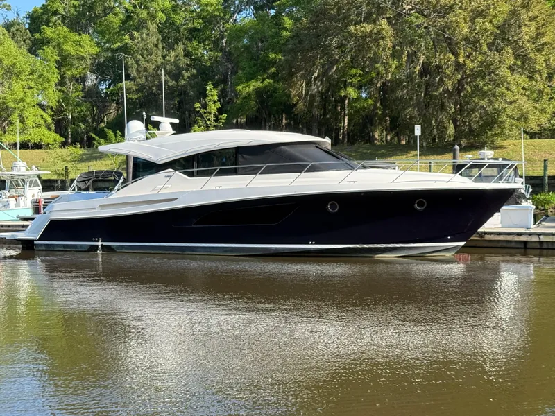 Slide: The Image of 2016 Tiara Yachts 50 Coupe docked on a calm river with lush greenery. - 3