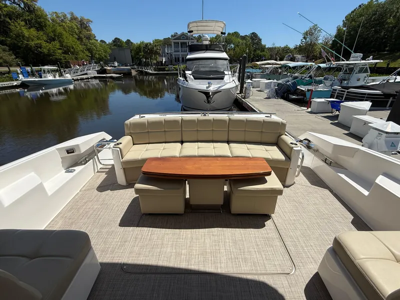 Slide: The Image of 2016 Tiara Yachts 50 Coupe with spacious outdoor seating and table, docked at a marina. - 9