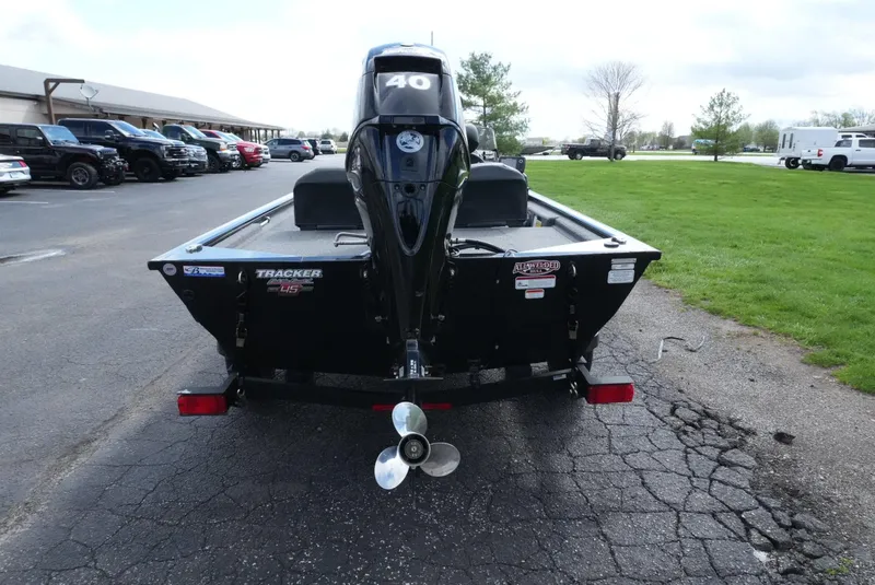 Slide: The Image of 2023 Tracker Pro 170 boat, rear view with motor, parked on asphalt near grass. - 11