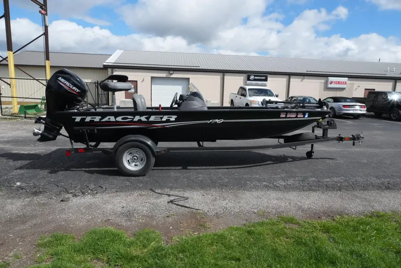 Slide: The Image of 2023 Tracker Pro 170 boat on trailer, parked outdoors near industrial buildings. - 6