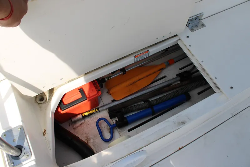 Slide: The Image of Storage compartment of a 2005 Boston Whaler 180 Dauntless with boating equipment. - 12