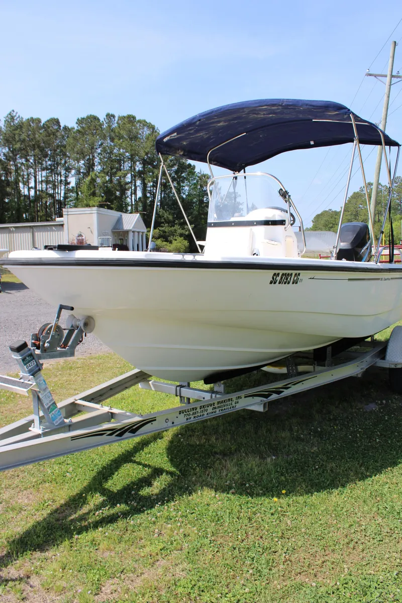 Slide: The Image of 2005 Boston Whaler 180 Dauntless boat on trailer with canopy, parked on grass. - 16