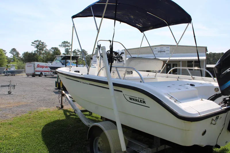 Slide: The Image of 2005 Boston Whaler 180 Dauntless boat on trailer with canopy, parked outdoors. - 4