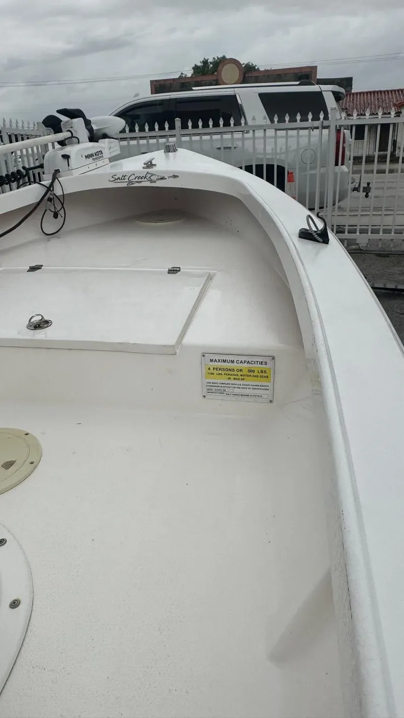 Slide: The Image of 2022 Salt Creek 1500 boat, white deck, parked near a fence on a cloudy day. - 14