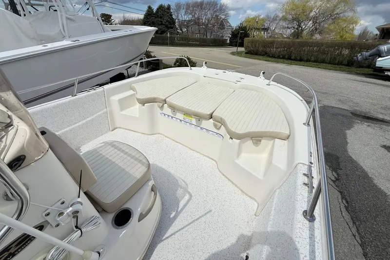 Slide: The Image of 2018 Carolina Skiff 198 DLV boat interior with seating and console, parked outdoors. - 5