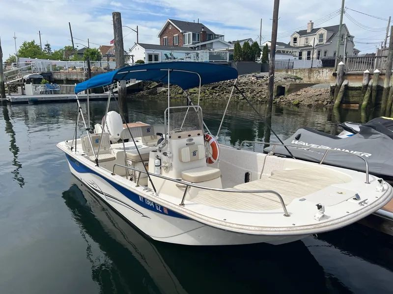 Slide: The Image of 2018 Carolina Skiff 198 DLV boat docked in a marina with blue canopy. - 6