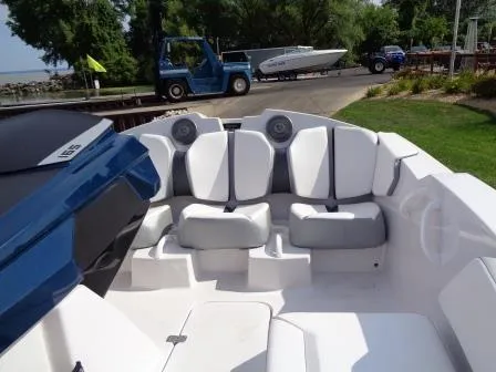 Slide: The Image of 2016 Scarab 165G boat interior with white seating and blue accents, docked near greenery. - 16