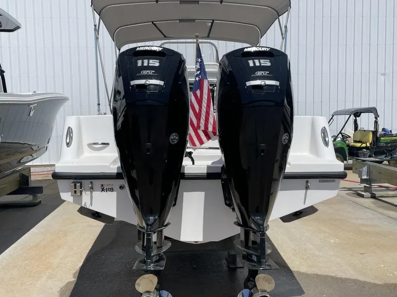 Slide: The Image of 2024 Reef Runner 230 XO boat with dual Mercury 115 engines, docked outdoors. - 13