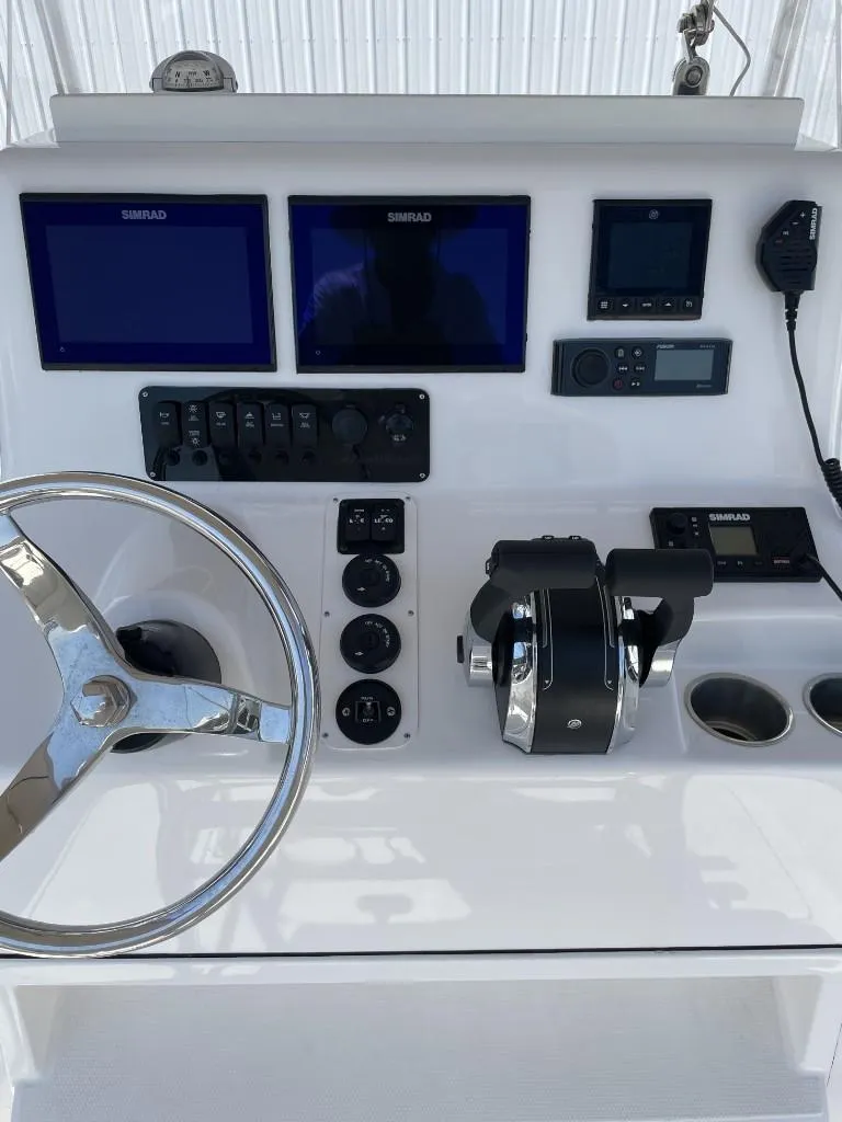 Slide: The Image of 2024 Reef Runner 230 XO boat dashboard with steering wheel and electronic controls. - 16