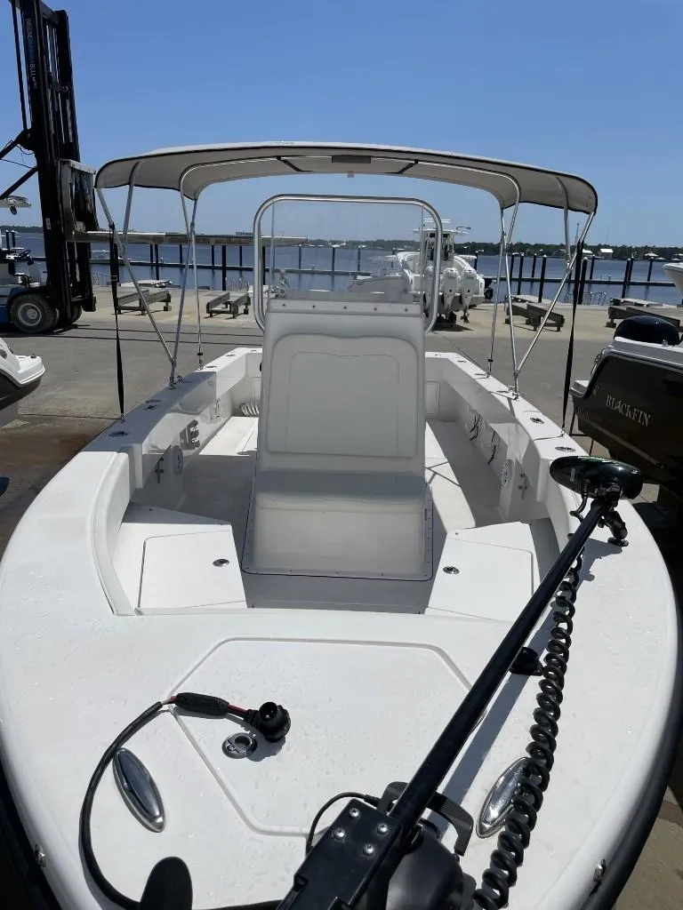Slide: The Image of 2024 Reef Runner 230 XO boat with canopy, docked at marina under clear blue sky. - 21