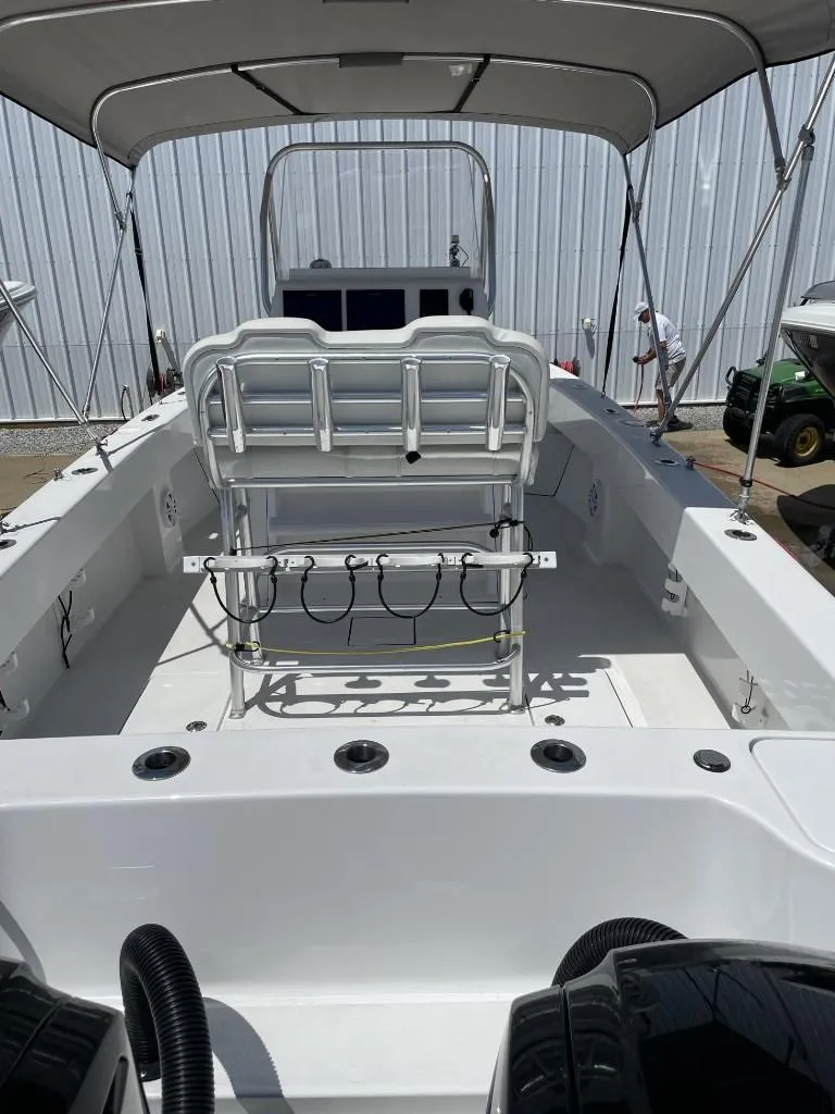 Slide: The Image of 2024 Reef Runner 230 XO boat interior with seating and canopy, docked near a metal building. - 22