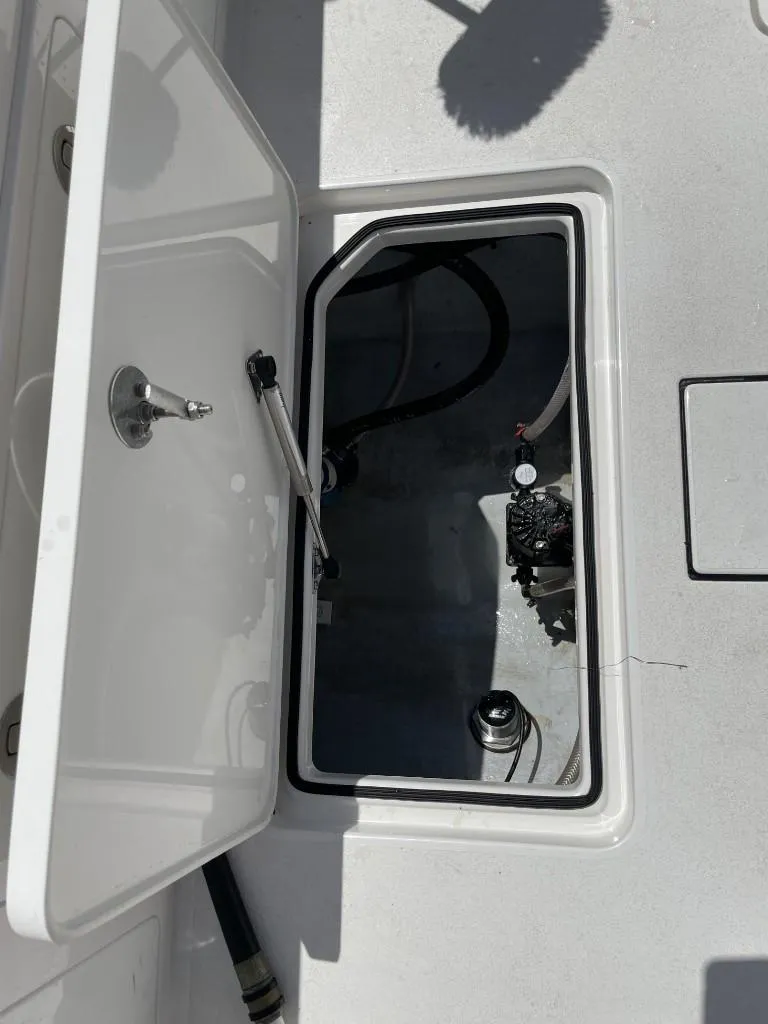 Slide: The Image of 2024 Reef Runner 230 XO boat storage compartment with open hatch and visible interior components. - 32