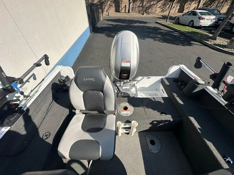 Slide: The Image of 2011 Lund 1625 Rebel XL Sport boat interior with seating and motor, parked outdoors. - 19